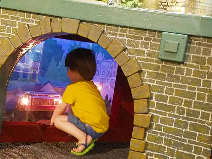 Child kneeling in a crawlspace inside the All Aboard exhibit.
